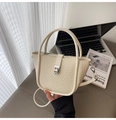 Detalle del bolso de mano crema con textura de cocodrilo y hebilla metálica plateada - Blanco