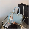 Gros plan d'un sac Boston bleu clair motif litchi avec breloque arc-en-ciel colorée - Bleu avec Pendentif