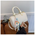 Gros plan du sac Boston crème avec texture litchi et breloque Love Is Eternal tressée - Blanc Cassé Avec Pendentif