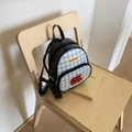 Detalle de patrón de cuadros y parche de manzana en una mini mochila negra brillante - Negro
