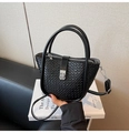 Detalle de un bolso tipo cubo negro con textura trenzada y cierre de metal giratorio - Negro