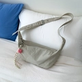 Khaki crossbody crescent bag with heart charm and woven tassel on white bedding - Light Gray