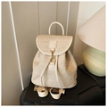 Detailed view of beige woven straw backpack featuring a metal hook clasp and fine texture - White