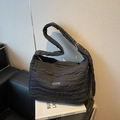 Sac fourre-tout matelassé noir avec plaque en argent sur un canapé en cuir noir - Noir