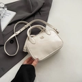 Petit sac carré crème élégant avec bandoulière réglable posé sur une veste grise - Blanc Sans Pendentif