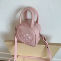 Close-up of pink heart-shaped mini bucket bag with white polka dots and silver zipper - Pink