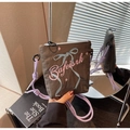 Detail of brown crossbody bag with pink lettering and blue bow embroidery on fabric - Gray