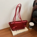 Sac cabas chic en cuir verni rouge avec bandoulière nouée posé sur des livres blancs - Rouge