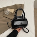 Elegante borsa a bauletto in pelle nera lucida con doppi manici e tasca frontale - Nero