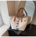 Detailed macro shot of blue telm embroidery and premium leather handles on canvas tote bag - Light Khaki