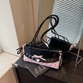 Rosa-schwarze Achseltasche mit Schleifendekor und Herzanhänger auf dem Tisch - 蝴蝶结荷叶边款式 / Rosa und Schwarz