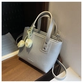 Détail du sac seau argenté avec texture lychee et un charm tulipe en tissu sur une table - Argenté