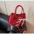 Détail d'un sac seau rouge à grain litchi avec un nœud décoratif en perles et dentelle - Bordeaux