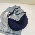 Dunkelblaue Nylon-Halbmondtasche auf Denim-Jacke mit Lifestyle-Requisiten - Blau