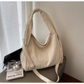 Close-up van de geplooide beige tote bag met verstelbare riem en verfijnde accessoires - Off-wit
