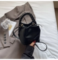 Detalle de bolso bucket de cuero negro con asa trenzada y cierre de cordón ajustable - Negro