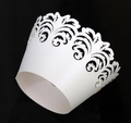 Macro detail of white laser-cut cupcake wrappers with intricate floral vine lace patterns - White