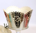 Vista macro di pirottini per cupcake dorati tagliati al laser con rose e cuori - Argento Riflettente