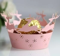 Close-up of pink laser-cut cupcake wrapper with reindeer silhouettes and golden chocolate - Pink