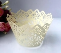 Detail of laser-cut cream cupcake wrapper with intricate floral vine pattern design - Ivory