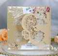 Macro view of champagne gold laser-cut invitation card with floral interior and lace detail - Beige Gold