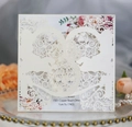 Close-up of laser-cut wedding invitation with intricate vine patterns and floral inner sheet - Ivory