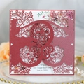 Macro detail of laser-cut wedding invitation showing intricate scrollwork patterns - Dark Red
