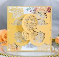 Close-up of laser-cut wedding invitation with gold hollow patterns and floral decor - Gold