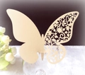 Détail d'un marque-place papillon doré découpé au laser avec motifs floraux sur un verre - Beige Étoile