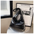 Dettaglio borsa hobo in pelle nera con grandi borchie in metallo argento su tavolo - Nero