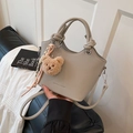 Light gray pebbled leather bucket bag with knotted handles and plush bear charm - Gray