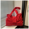 Detail of red bow-shaped tote bag with textured nylon fabric on a white windowsill - Red