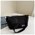 Close-up of black canvas crossbody bag with Fashion logo tag and wide fabric strap - Black