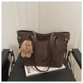 Detail of dark brown matte suede tote bag with plush bear charm on a black chair - Coffee with Pendant