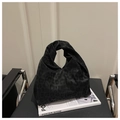Dettaglio della borsa tote leopardata con manico intrecciato su una rivista minimalista - Nero