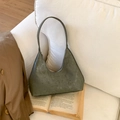 Detalle de bolso de hombro en cuero verde oscuro sobre un libro antiguo con luz suave - Verde