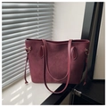 Close-up of a burgundy suede tote bag with leather trim and gold metal hardware - Red Without Charm