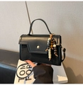 Close-up of black leather crossbody bag with geometric flap and colorful wood tassel - With Pendant / Black