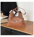 Vista detallada del bolso tote marrón con hebilla de metal dorado en mesa de madera - café