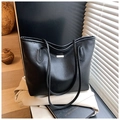 Close-up of black lychee grain tote bag with metal logo detail in minimalist setting - Black