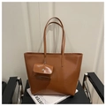 Grande borsa tote marrone con mini portamonete su una sedia dal design moderno - Marrone