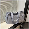 Detailaufnahme der nebelblauen Nylon-Tragetasche mit Seitentaschen und Modeweblabel - Blau