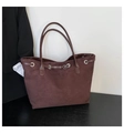 Detail van donkerbruine suède tote tas met leren handvaten en zilveren metalen oogjes - koffiekleur