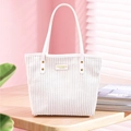 Detalle de bolso tote de pana blanca con remaches dorados y etiqueta de moda - Blanco