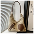 Primer plano del bolso tote de lona con bolsillos de cuero marrón y cremalleras de metal - Caqui