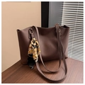 Détail d'un sac cabas en cuir marron avec surpiqûres blanches et foulard en soie décoratif - café