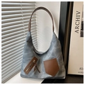 Detalle del bolso tote de mezclilla azul con correas de hombro de cuero marrón y bolsillos - Azul