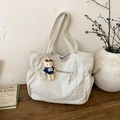Detalle del bolso tote de pana blanco crudo mostrando textura acanalada y colgante de oso - Blanco Con Colgante