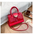 Detailansicht der roten Handtasche mit Krokodilmuster, goldenem Drehverschluss und Riemen - Rot