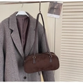 Primer plano de un bolso de ante marrón oscuro colgado en un abrigo de lana con estilo vintage - café